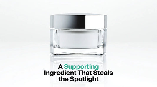  A square, clear glass jar of white cream with a reflective silver lid is centered on a white surface, with the text overlay "A Supporting Ingredient That Steals the Spotlight".
